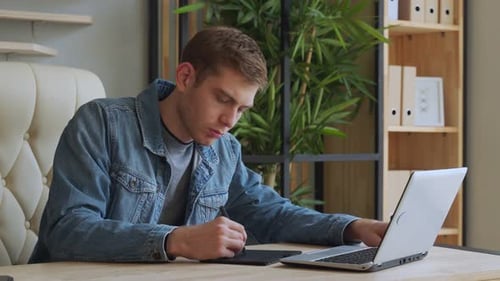 Young Man Designs on Tablet and Laptop