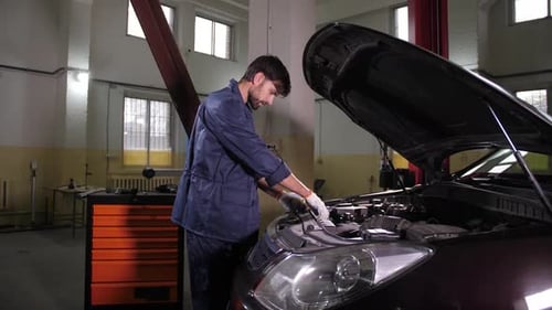 Mechanic Inspecting Car Engine in Automotive Repair Shop