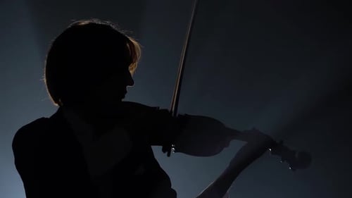 Violinist Performing in a Dark Studio with a Lantern. Black Background. Silhouette