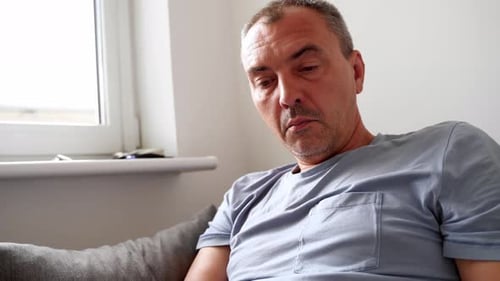 Adult Man Relaxing with Smartphone on Couch Indoors