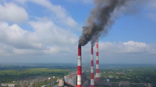 Industrial Smokestacks Billowing Smoke into Blue Sky