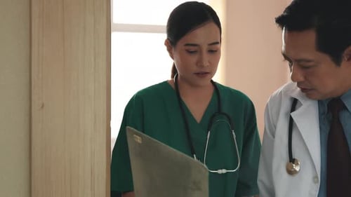 Doctor and nurse with medical report talking while walking down hallway at the hospital