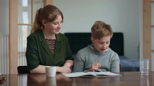 Boy Writes Answers on His Textbook with His Sister Guiding Him