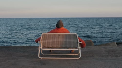 Single Old Man on Sits on a Bench Seaview Homeless Guy Backview Watching Sunset Near Sea Ocean
