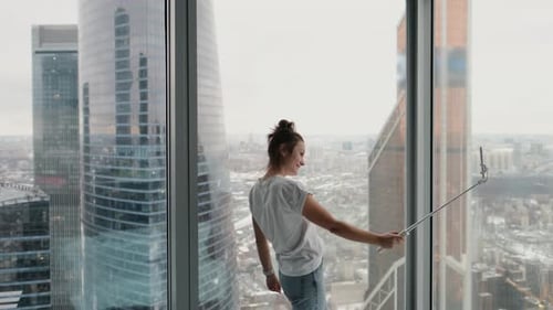 Attractive Girl Tourist Taking Selfie Near Window in Modern Hotel with City View From High Floor