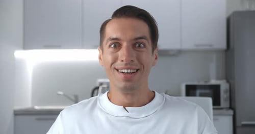 Excited young man cheers in his kitchen