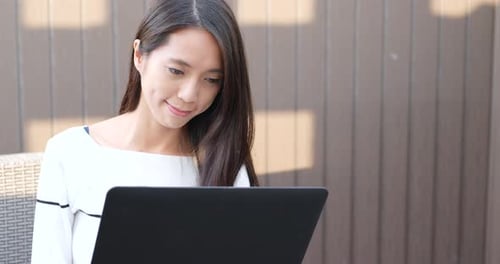 Woman working on laptop computer at outdoor coffee shop