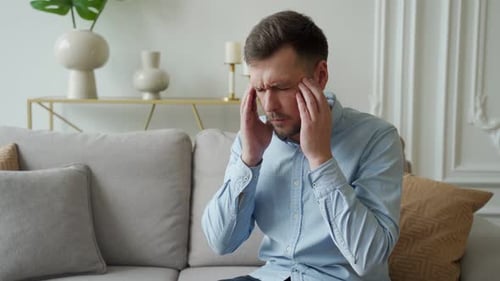 Man Rubbing Temples with a Headache Indoors