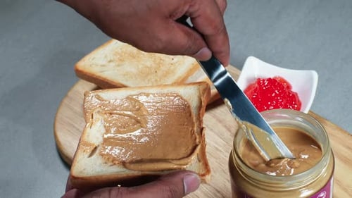 Adult Spreads Peanut Butter on Toast