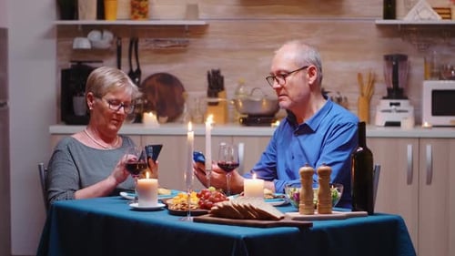 Mature Couple Uses Phones at Dinner Table