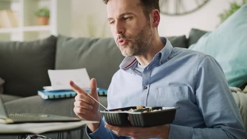 Man Eating Lunch In Front of Laptop at Home