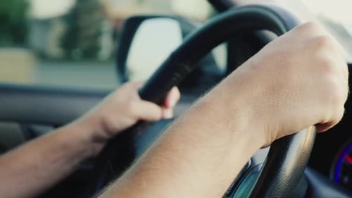 Die Hände des männlichen Fahrers am Lenkrad des Autos