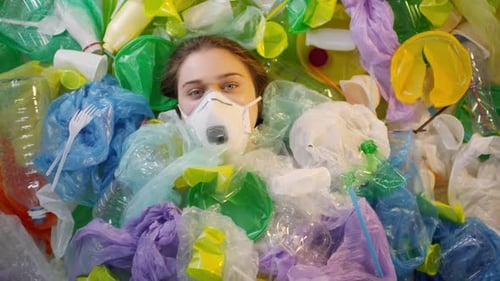 Young Adult in Face Mask Surrounded by Plastic Waste