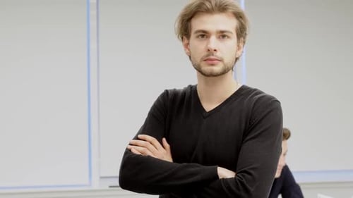 Man Stands With Arms Crossed in Workplace