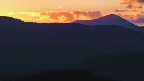 Beautiful Evening Panoramic Landscape with Bright Setting Sun Over Distant Mountain Peaks at Sunset