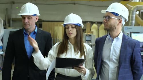 Factory Workers Discuss Plans with a Clipboard