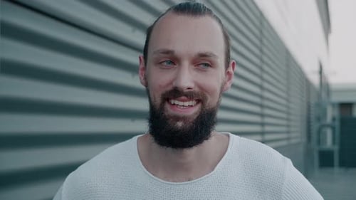 Smiling Bearded Millennial Hipster with Blue Eyes Looking at Camera
