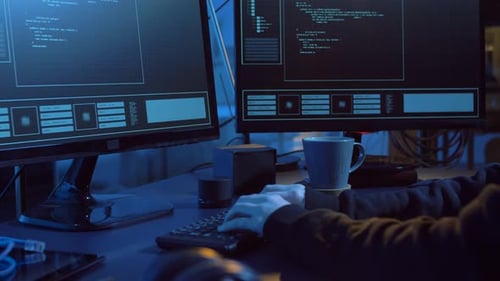 Person Coding at Computers in Dark Room