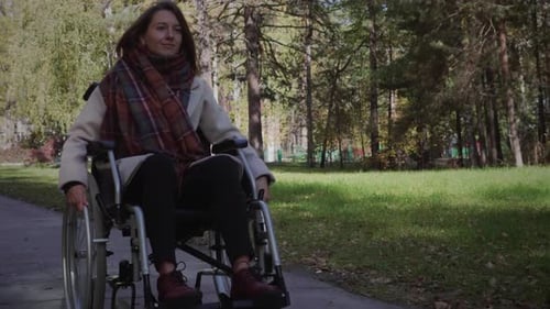 Woman in Wheelchair Rolls Through Autumn Park