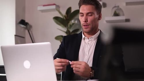 Businessman Having Online Talk in Front of Laptop and Sitting at Table in Modern Office Spbi