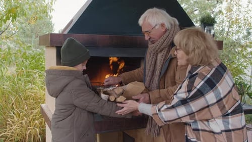 Grandparents Preparing Fireplace with Grandchild Assistance Outdoors