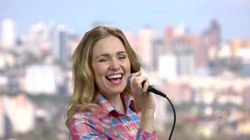 Young Woman Singing With Microphone and City Background