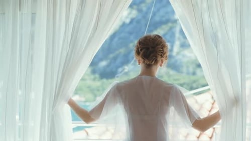 Woman Opens Curtains to Beautiful Mountain View