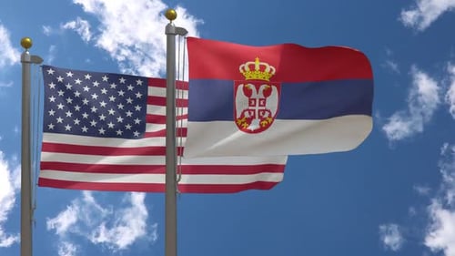 United States and Serbian Flags Waving Against Blue Sky