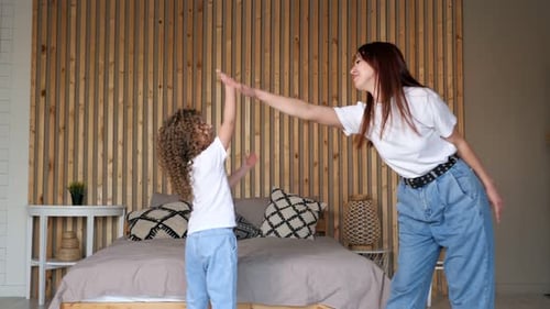 Delighted Mum and Preschooler Girl Jump Up Dancing with Joy