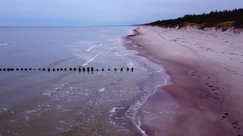 Beautiful aerial view of an old wooden pier at the Baltic sea coastline, overcast day, white sand be