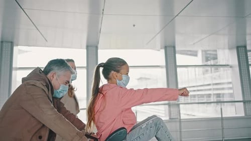Little Girl Sitting in Luggage Cart and Gesturing Like Superhero Her Parent Riding Her to Flight in