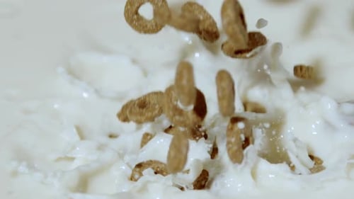 Cereal Pieces Falling Into Bowl of Milk