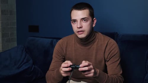 Young Man Playing Video Game on Blue Couch