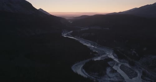 Aerial helicopter shot, circle around tall buildings at the tail end of sunset, city lights, drone f