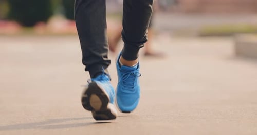 Legs and Sneakers Jogging on Paved Path