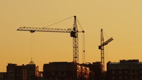 Cranes Silhouetted Against City Sunrise Skyline