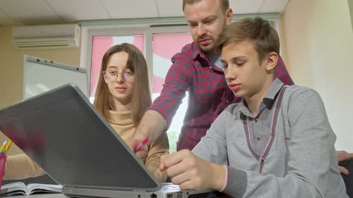 Teacher Helping Students With Laptop Computer Work