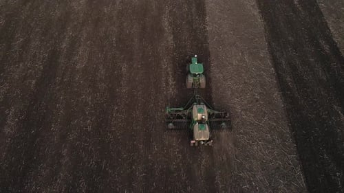 Aerial view, drone view of green tractor with plough working on a field,