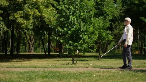 Blinde Rentner navigieren sicher mit weißem Gehstock, gehen unabhängig im Park