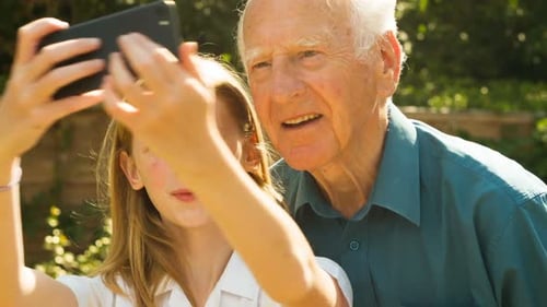 Girl Takes Cheerful Selfie with Grandfather in Garden