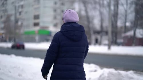 Woman Walking with Cane on Snowy Urban Street