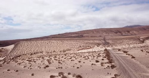Path road in the middle of a mountains sand desert with blue bright sky in background. Arid climate