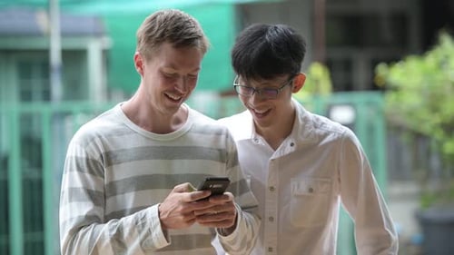 Two Smiling Young Adults Looking at a Phone