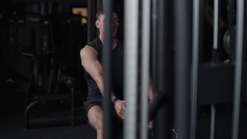 Man in the Gym Lifting Blocks on Rowing Machine Training on Block Device and Gym Equipment Night