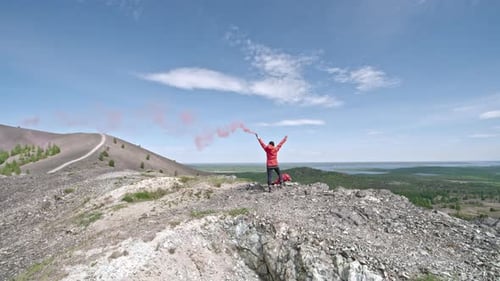 Rear View of Hiker in Mountains with Smoke Grenade