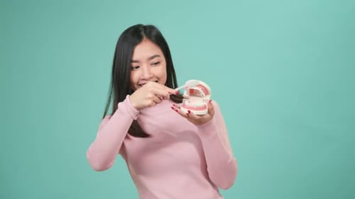 Woman Demonstrates Brushing Teeth with Braces Model