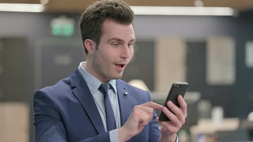 Excited Man Using Smartphone in the Office