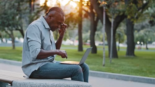Adult Man Works on Laptop in Urban Park
