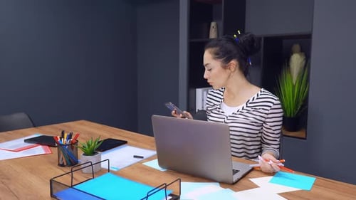 Woman Working at Desk with Laptop and Smartphone