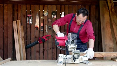 Man Cuts Lumber With Chop Saw in Workshop